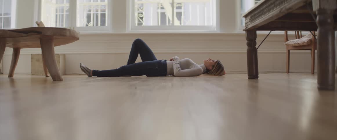 A woman lays on the floor underneath a large window
