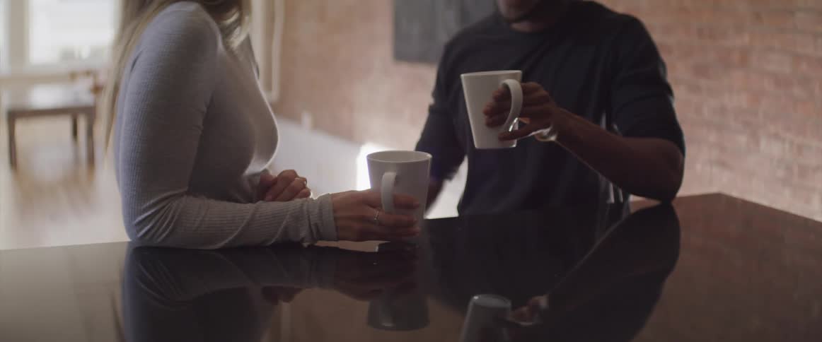 Two people toast their mugs and take a drink