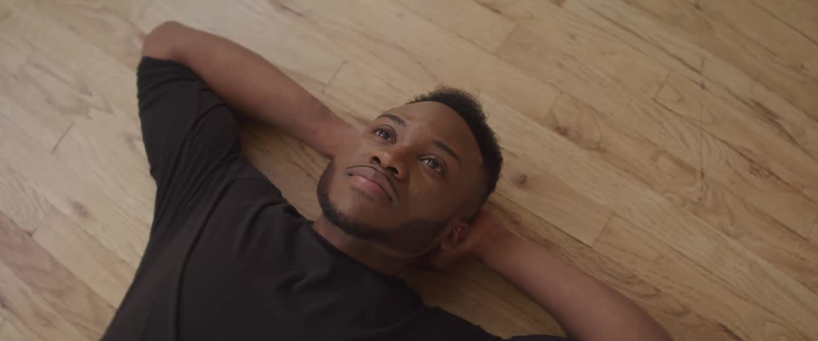 A man lies on the floor thinking