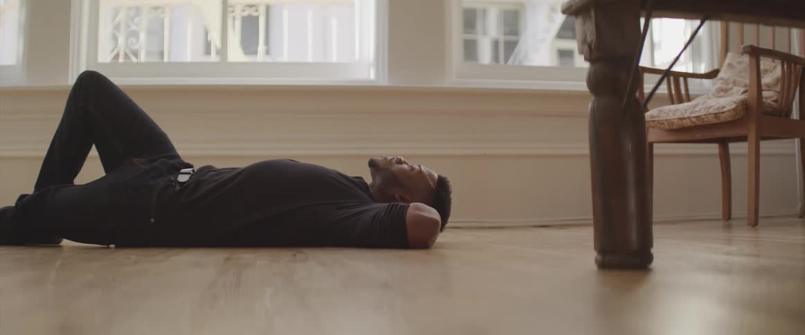 Young man laying on the floor of a room at day