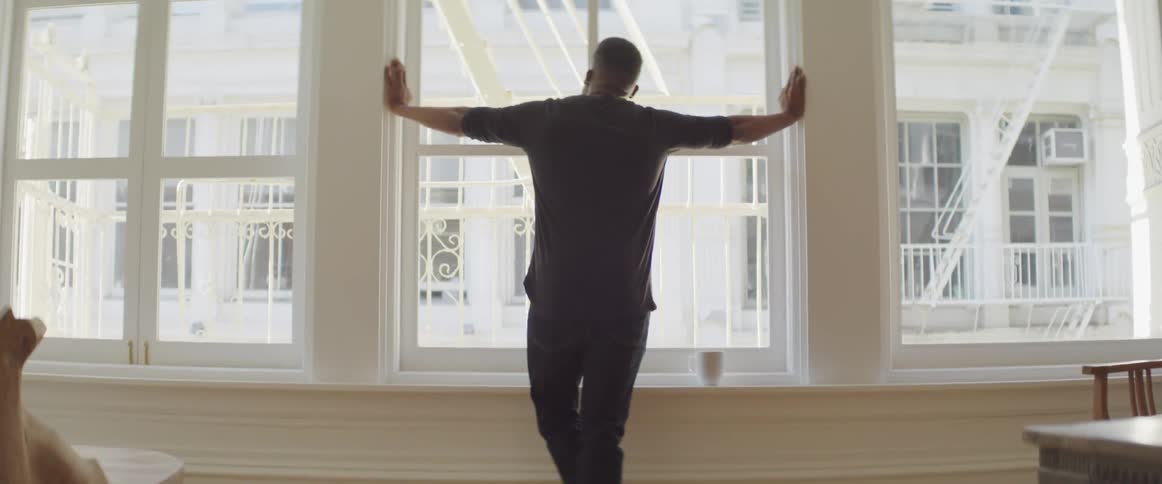 Black man looks out the window in the apartment
