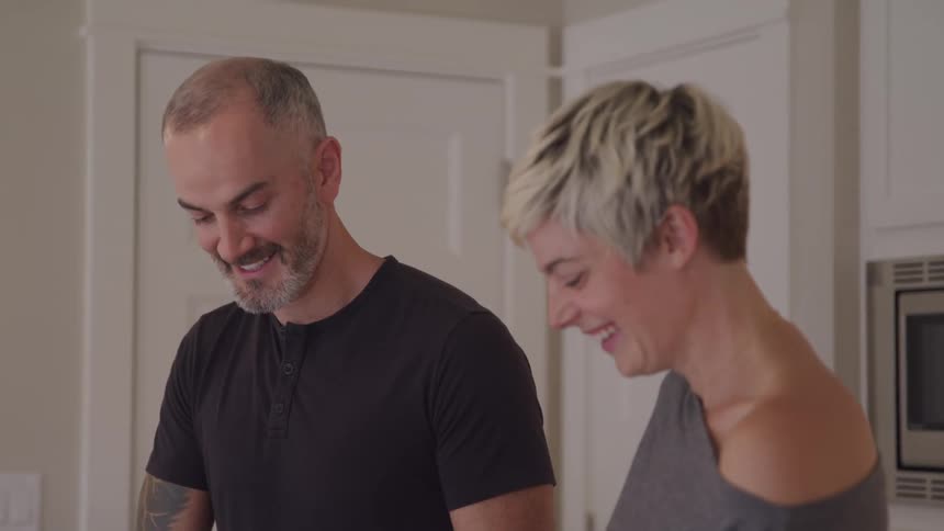 Couple talking and laughing in the kitchen of an apartment
