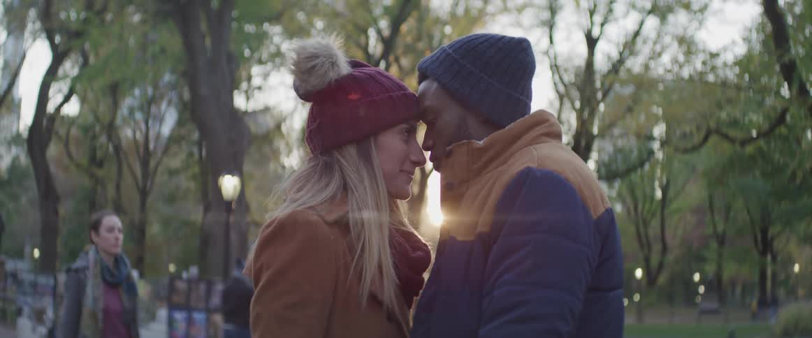 Black man and white woman stand face to face in the public park
