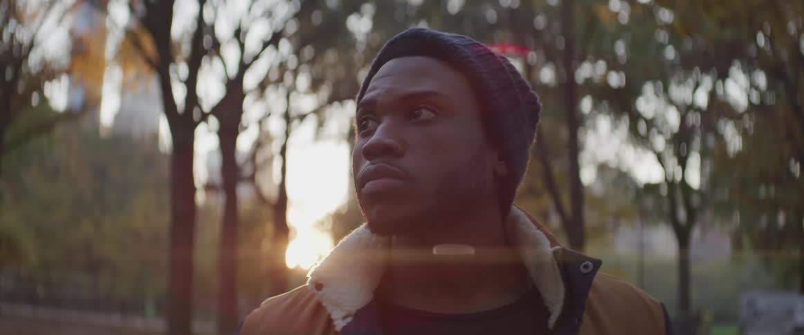 Man stands on park at sunset looking away