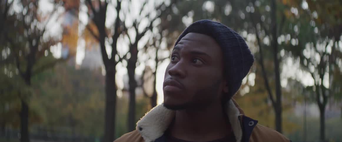 Black man raises his head and looks sideways at sunset in the public park