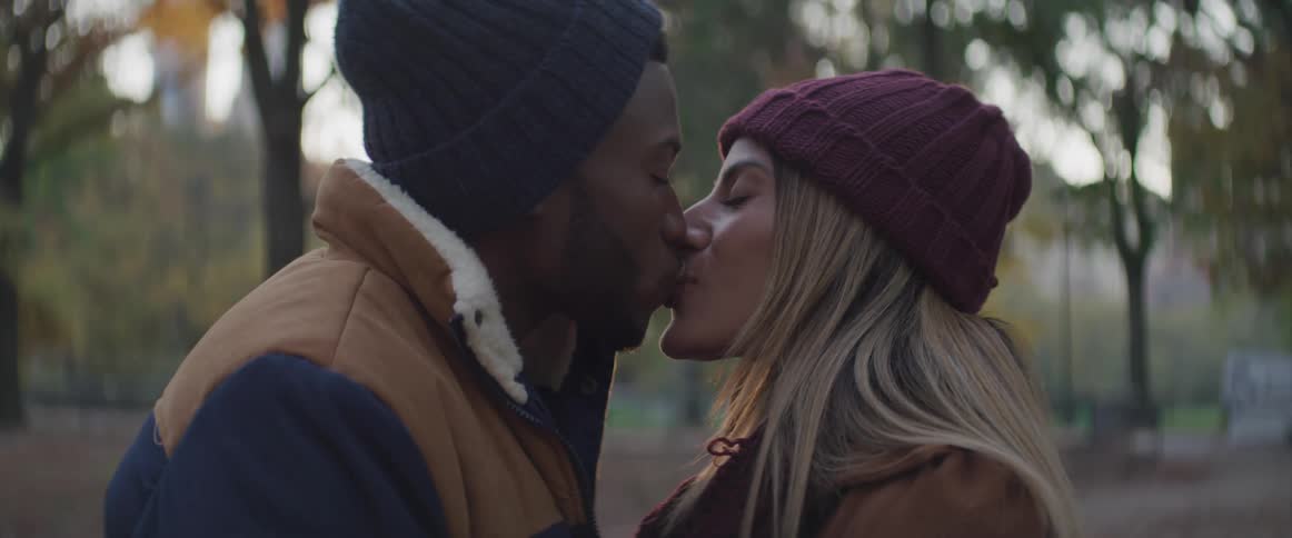 Young couple kiss in the park at sunset