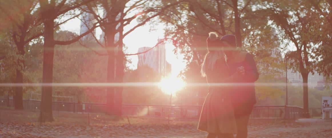 A man and woman slow dance together in a public park