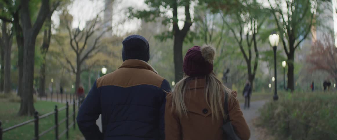 Black man and white woman walks in the public park