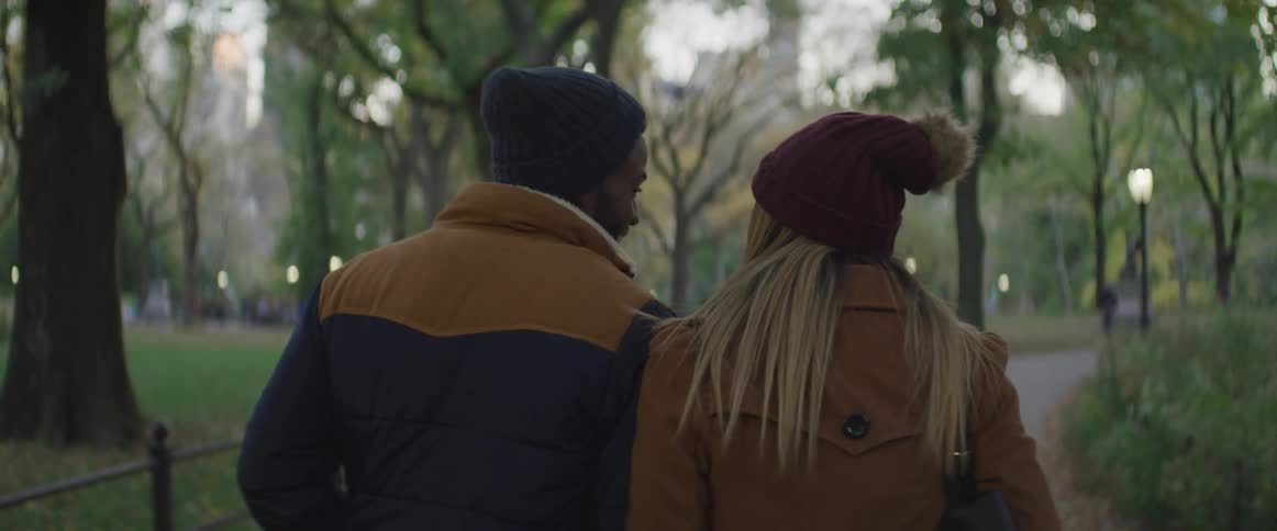 A man and woman walk together through a public park