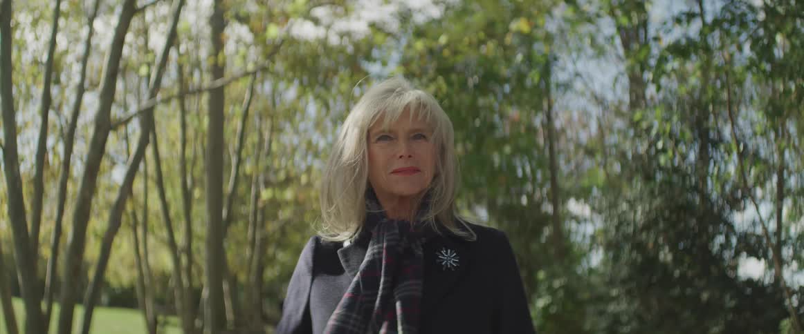 Senior woman looking sideways turns her head to the camera in the public park