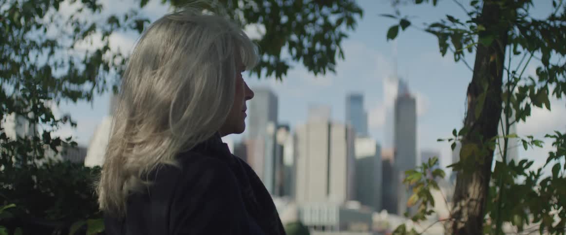 Woman sitting on the bench watches the tall buildings and skyscrapers