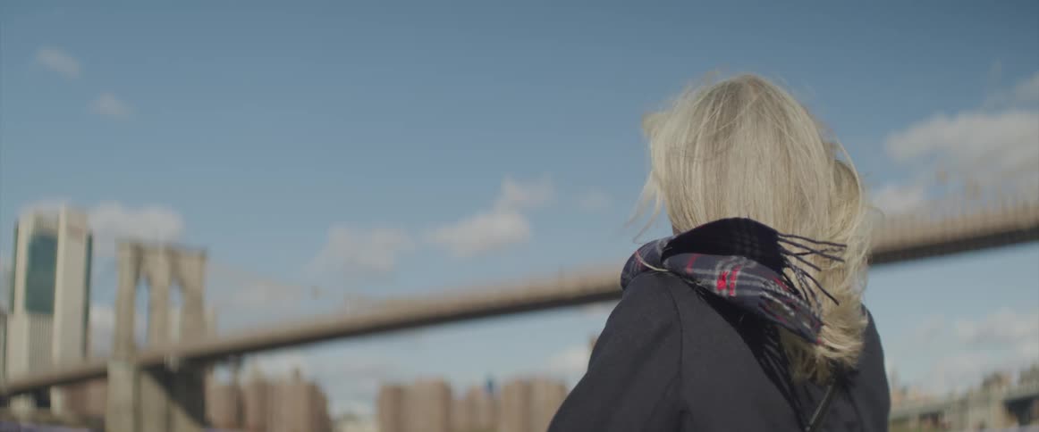 A woman looks over towards a bridge on a windy day