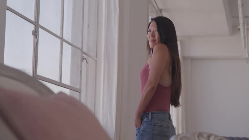 A woman stands in a living room admiring her clothes