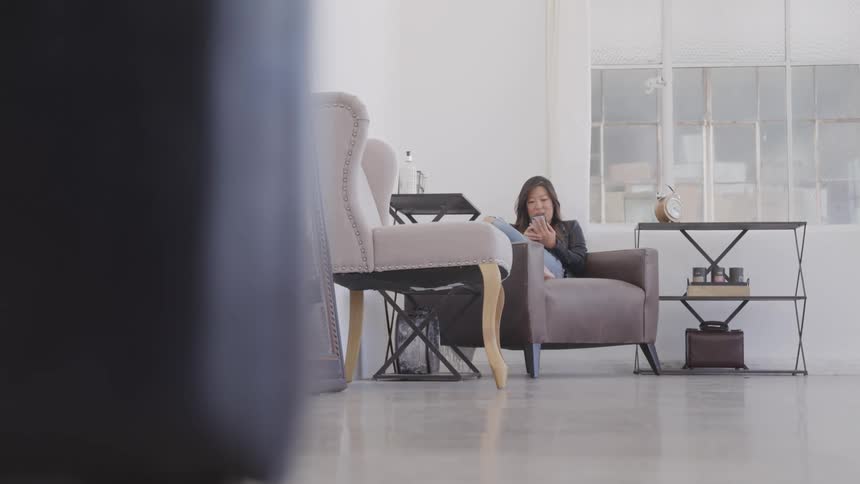 A woman sits with her legs up on her couch and uses her smart phone
