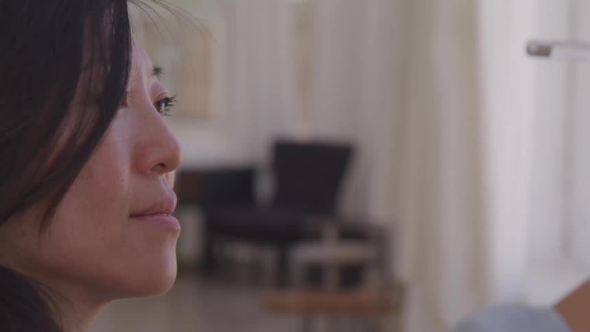 Asian woman paints on the canvas in the living room