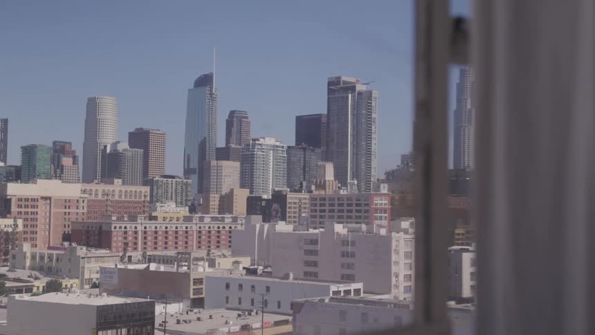 City skyscrapers and surrounding buildings show through window against blue sky
