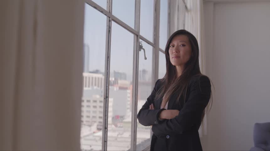 A woman stands by her window