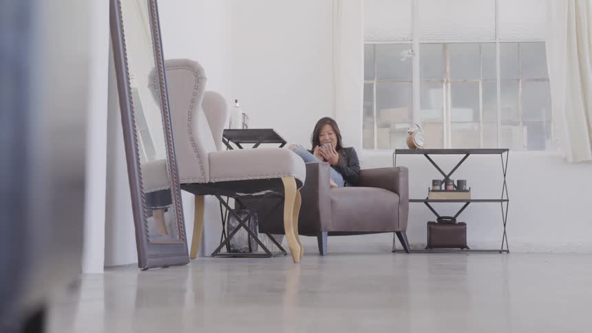 Asian woman sitting on the sofa uses a smartphone