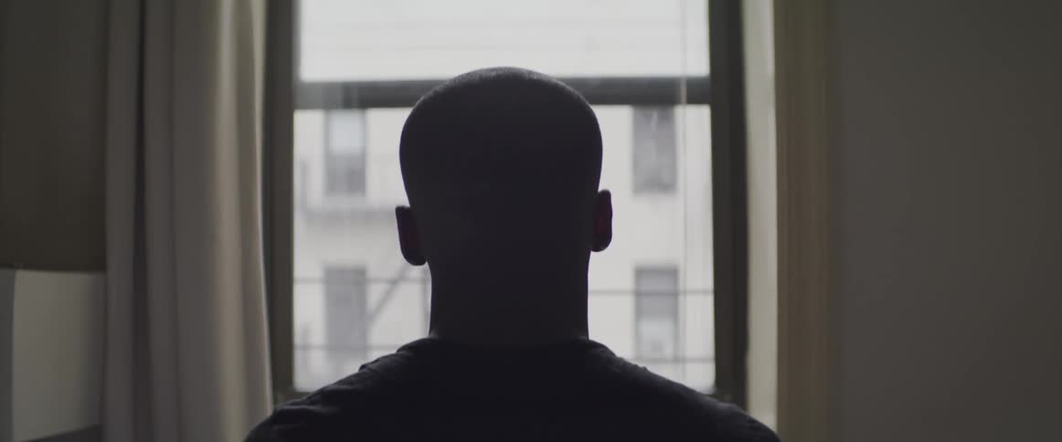 Black man sitting on the couch looks out the window