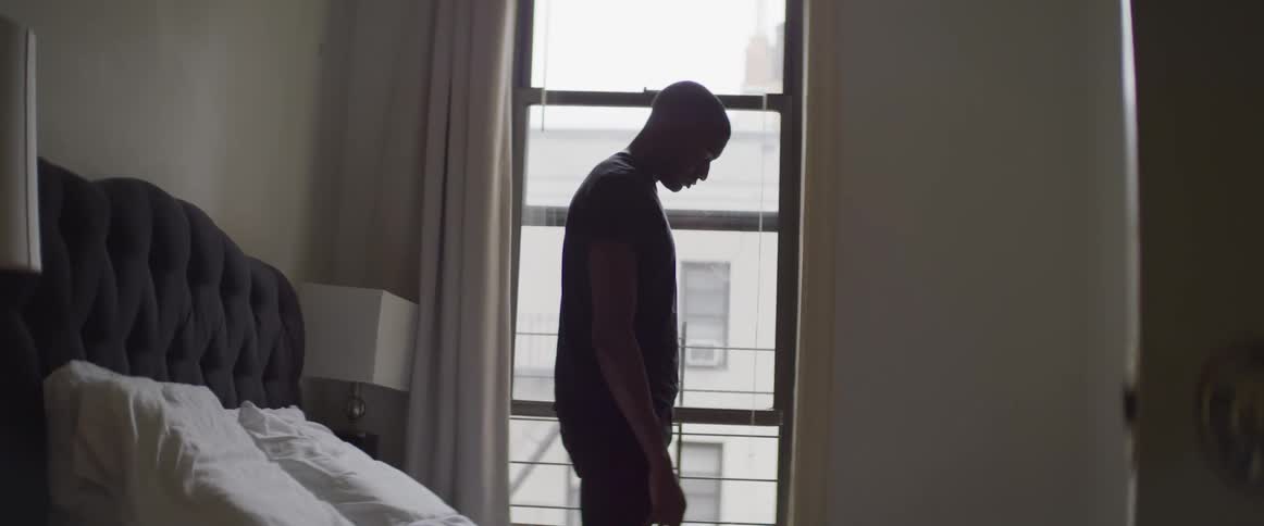 A man stands in a bedroom with his head facing down