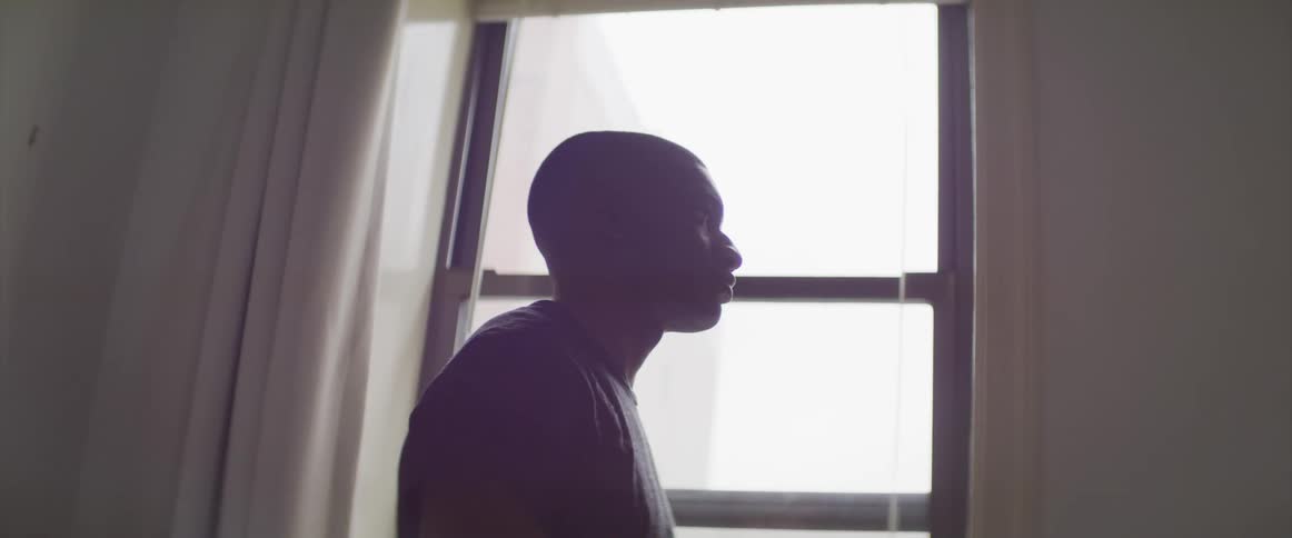 A man stands next to a window in his apartment building