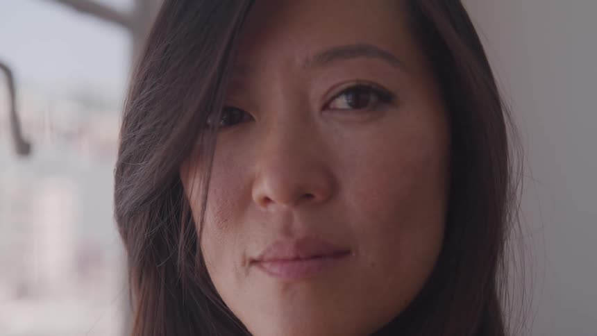 An asian woman turns and looks ahead