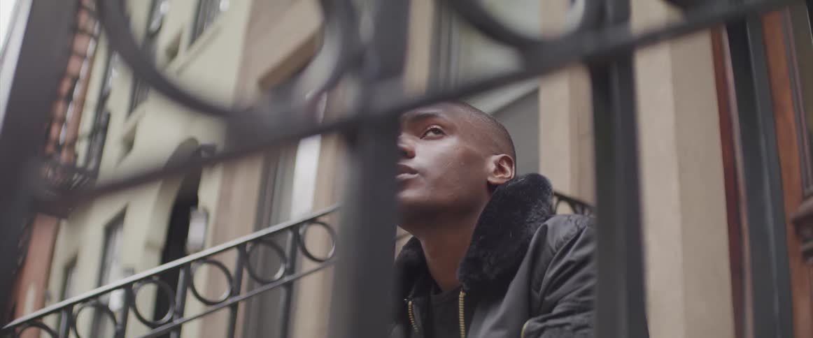 Young black man sitting on front steps of an apartment building