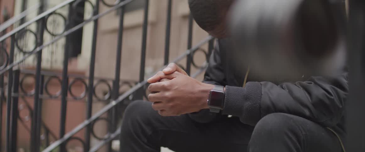 A man is sitting and leaning over on the steps