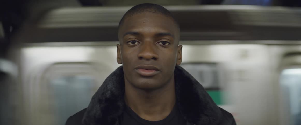 A black man sits on a train