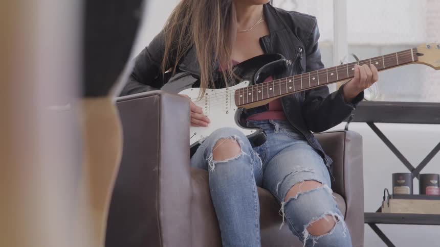 Woman plays a guitar as she sits in a chair
