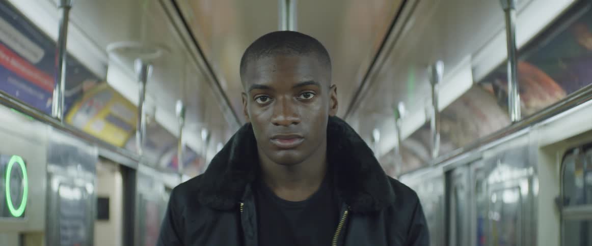 Young black man standing inside a subway train