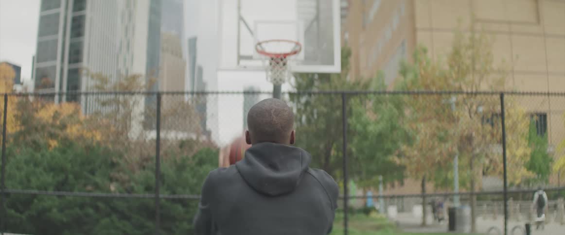 Black basketball player takes a free throw in the public basketball court