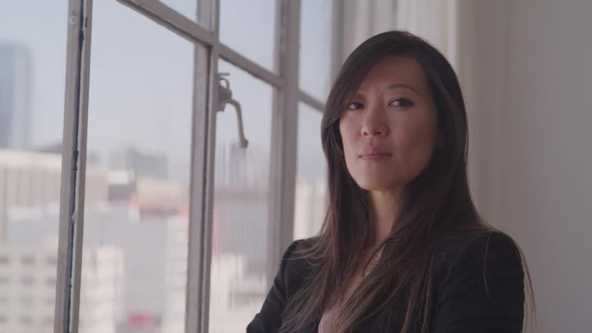 Business woman looking out the window turns her head and stares at the camera in the office