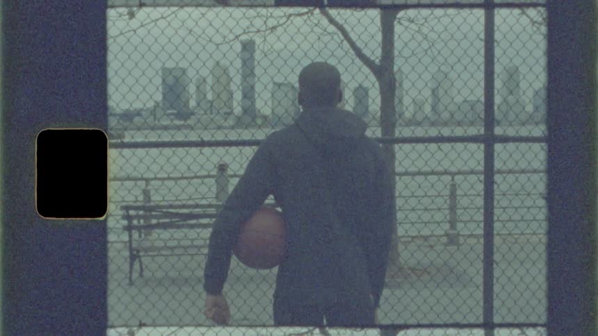 Teenager standing with a basketball looking across the harbor to the city