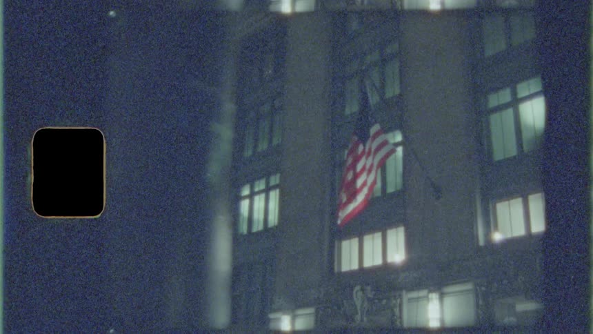 A flag blows in the wind attached to a city building