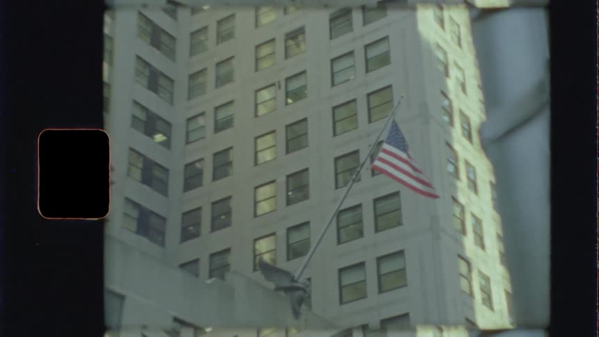 American flag flies on a pole near a tall building
