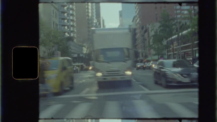 A city street with a crosswalk vehicles buildings and the sky in the background