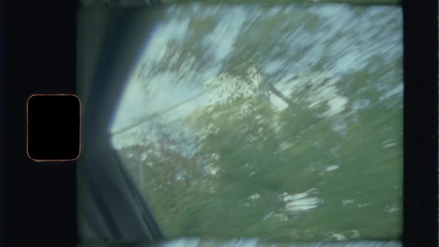 A car window with trees and a bridge in the background