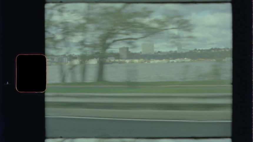 A road runs parallel to a city skyline visible across the ocean