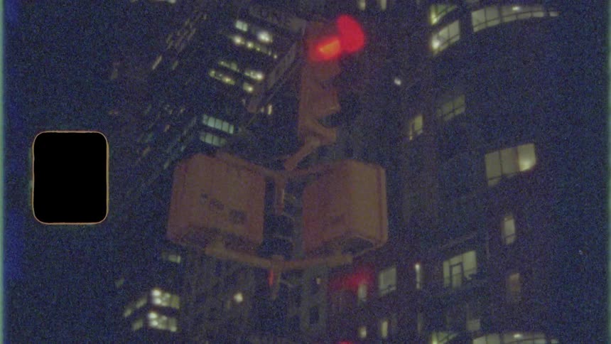 A traffic light changes from yellow to red in front of a tall office building at night