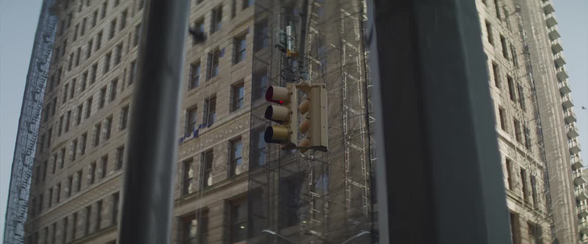 A tall apartment building sits at an intersection with a traffic light stopped on red