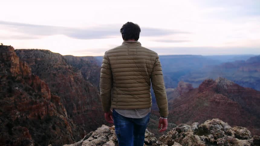 Man approaches a mountain ledge overlooking the valley