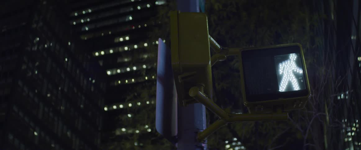 Pedestrian street crossing signal in the middle of the city at night displays the walk sign