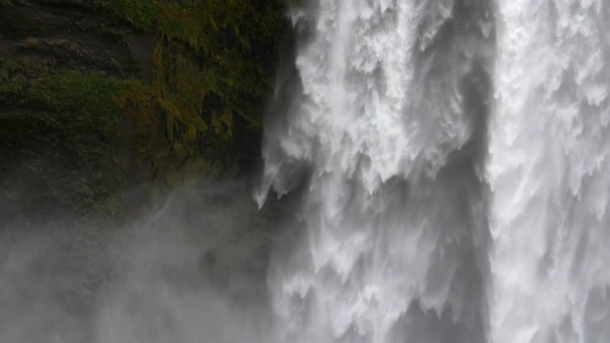 A large waterfall cascades down as mist rises