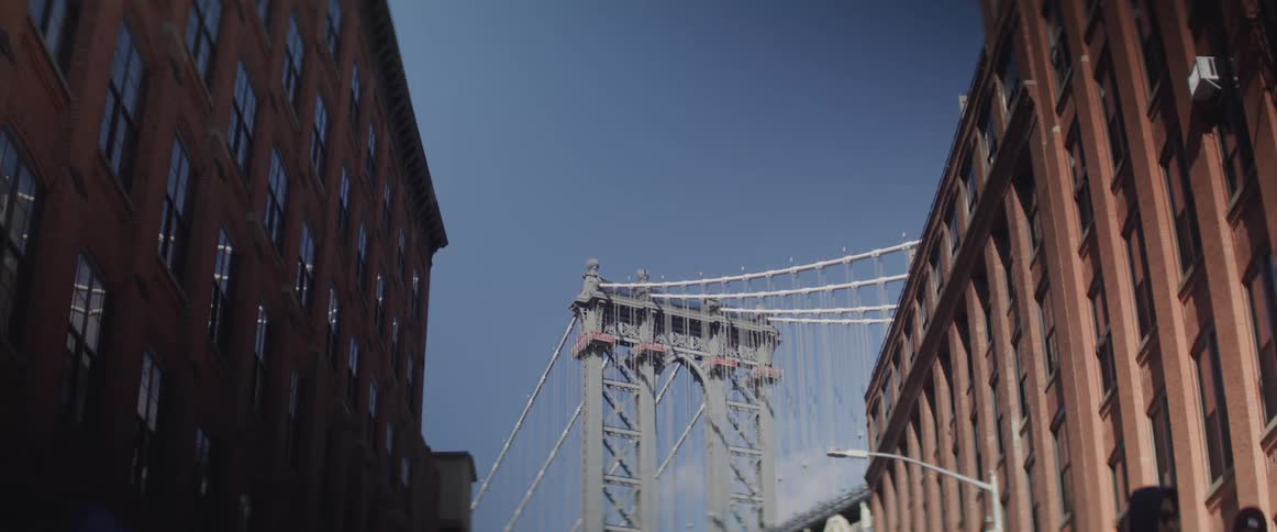 A city street with buildings people and a bridge in the background