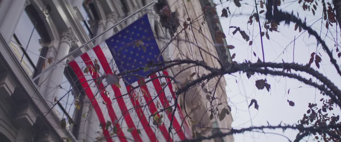 An american flag mounted on the facade of a building waving gentle in the wind