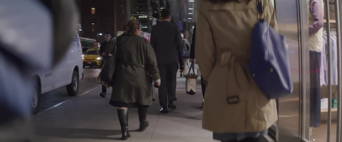 Pedestrians walking down the sidewalk of a city at night