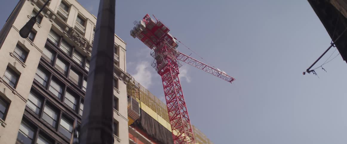 A red crane is parked next to ongoing construction at a high rise building