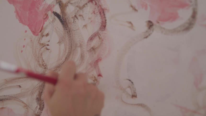 A woman draws a rose with watercolor paint on canvas
