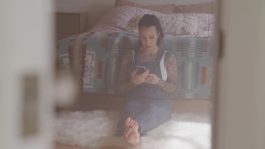 A woman is using her phone in the bedroom